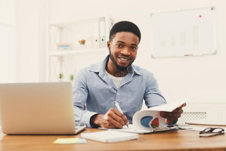 black businessman working laptop taking notes modern white office interior smiling employee work computer copy 122517513